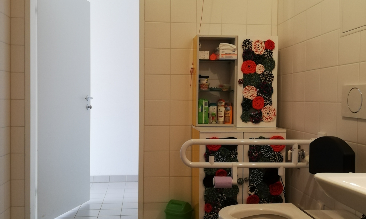 Barrierefreies Badezimmer mit Waschbecken, Toilette, Schrank im Bild